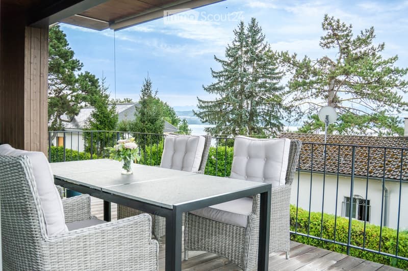 Balcony with a view, featuring a table, chairs, and a vase with flowers.