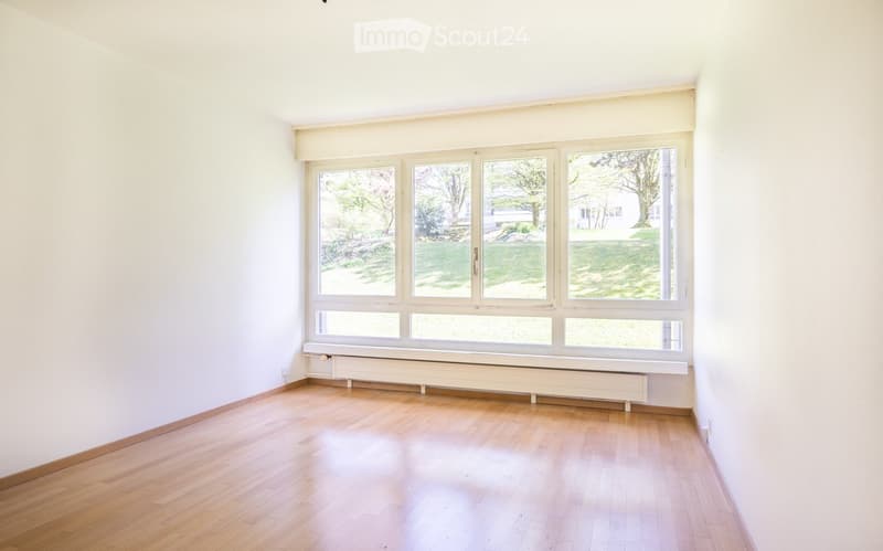 empty room with large windows, wooden floors, and white walls