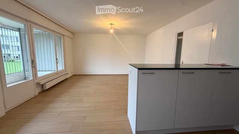 wooden floor, modern kitchen with granite countertops, sliding doors leading to a balcony, large window with view