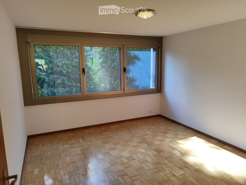 Empty room with wooden flooring, large windows, and natural light. No furniture or equipment present.