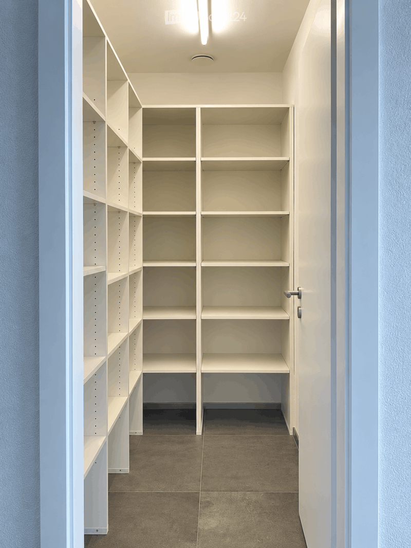Empty closet with white built-in shelving units and a tiled floor.