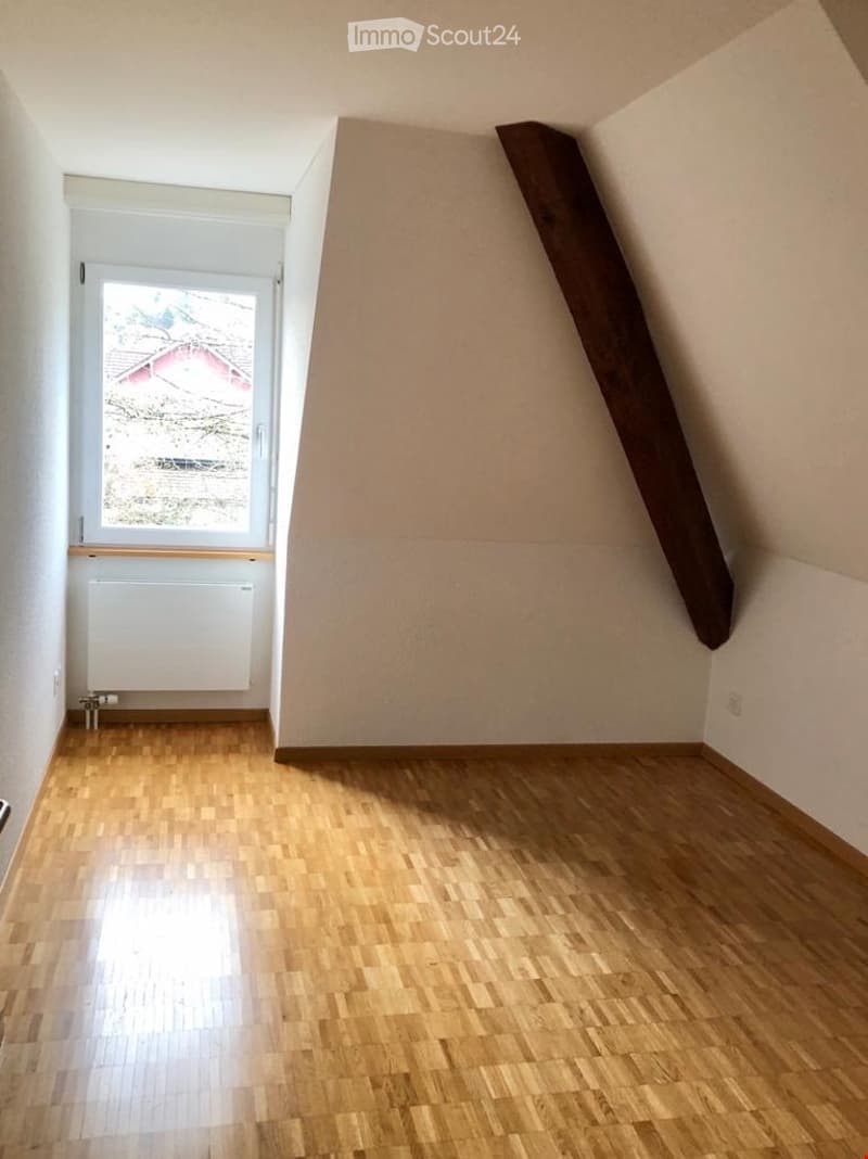 Empty room with wooden flooring, white walls, and a window with a view of the outside. No furniture or equipment is present.