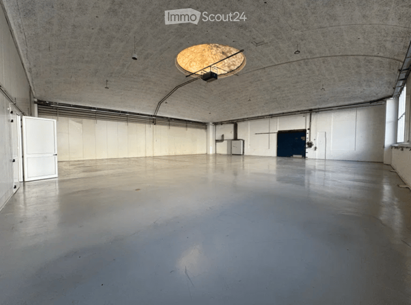 Empty room with bare walls, polished concrete floor, and a single hanging light fixture.