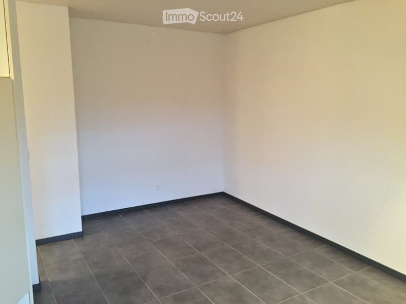 Empty room with beige walls and dark tiled floor, no furniture or equipment visible.