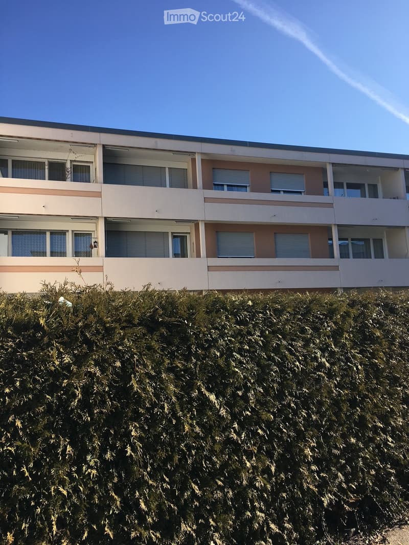 Multi-story residential building, rectangular balconies, beige walls, windows with shutters
