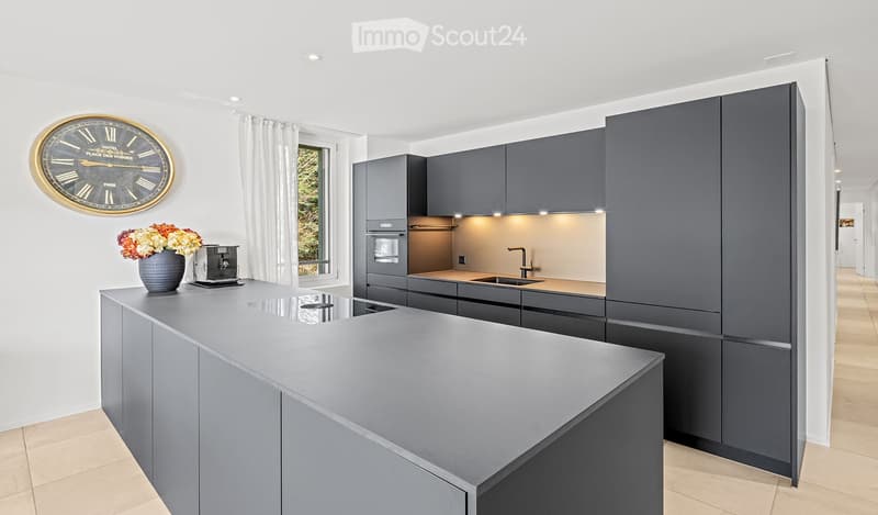 Modern kitchen with grey cabinetry, a central island, built-in appliances, and a sleek design.