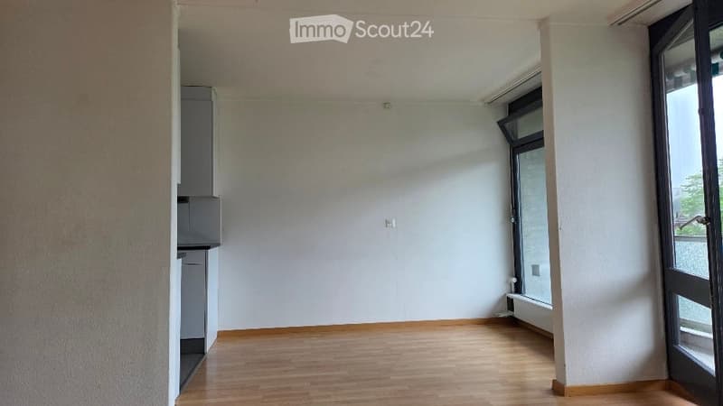 Empty room with wooden flooring, white walls, and large windows. No furniture or equipment present.