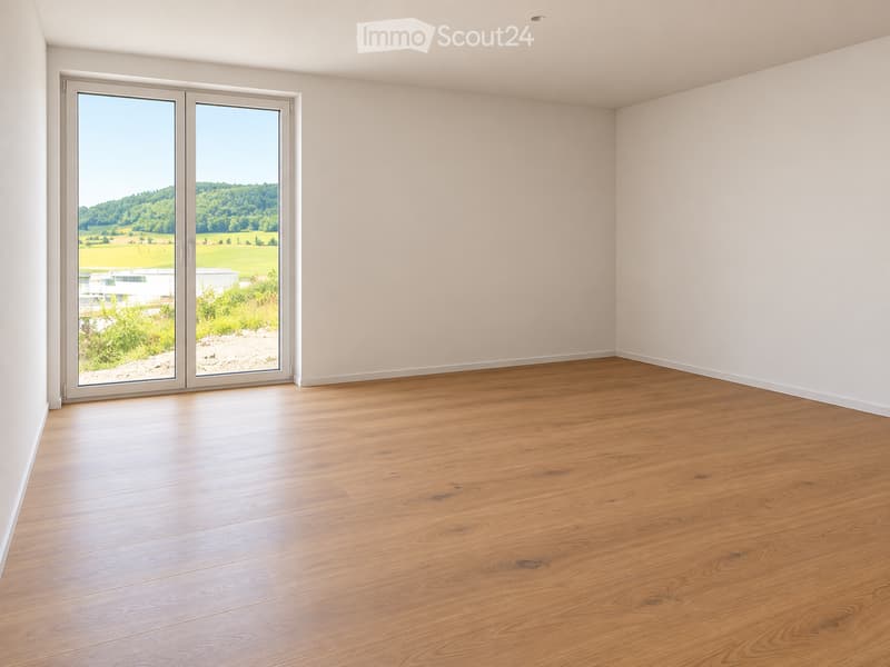 Empty room with light wooden flooring and large sliding glass doors leading to a scenic outdoor view.