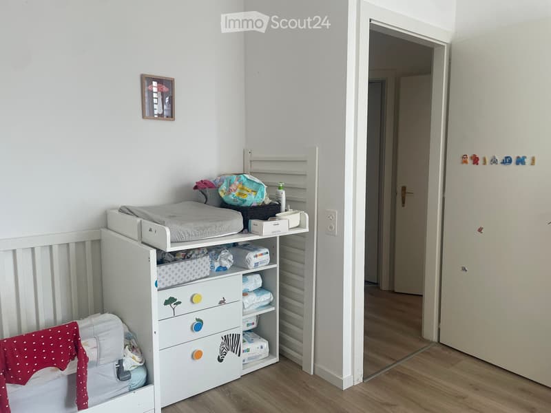 A well-organized nursery with a crib, changing table, storage unit, and various baby items.