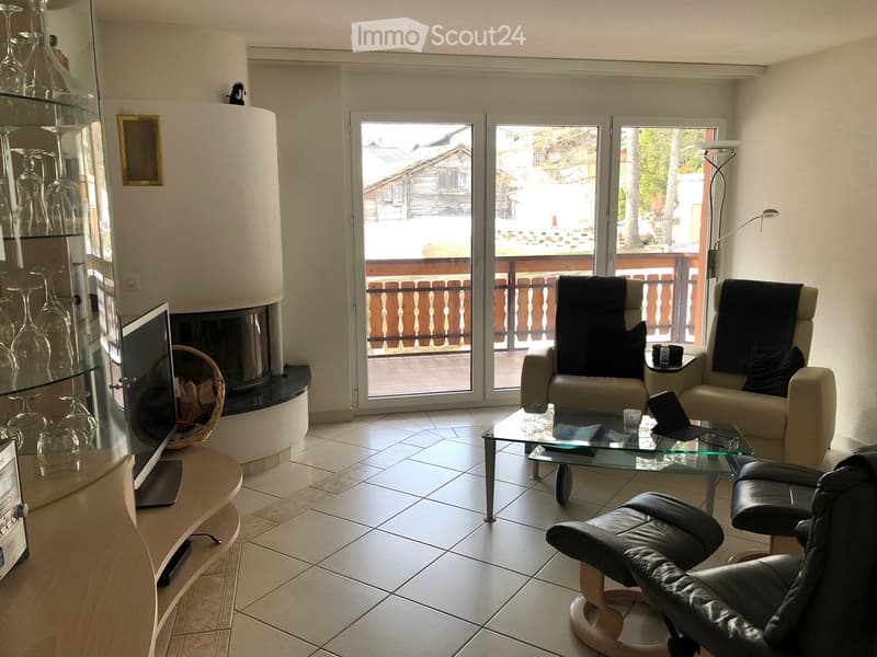 Modern living room with a fireplace, large glass doors leading to a balcony, a sofa, chairs, a coffee table, and a wine rack.
