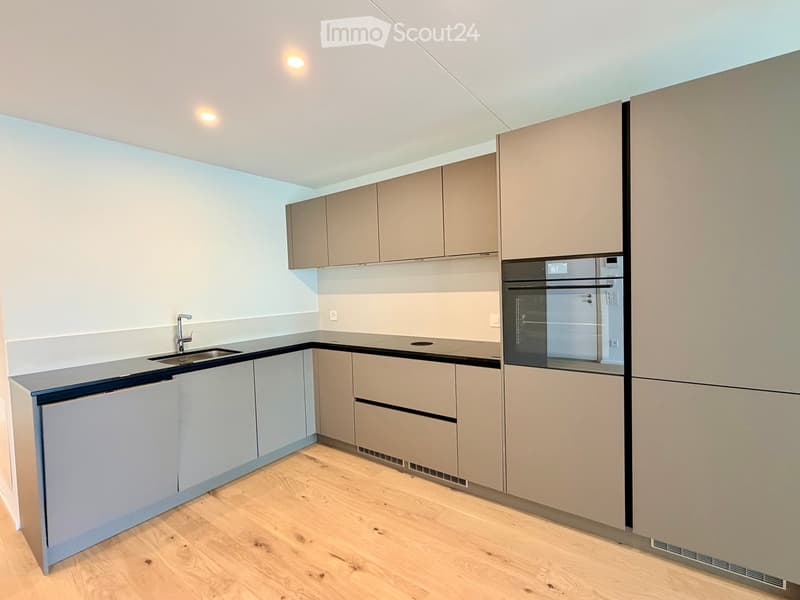 Modern kitchen with light-colored cabinets, a stainless steel sink, and built-in appliances including an oven and refrigerator.