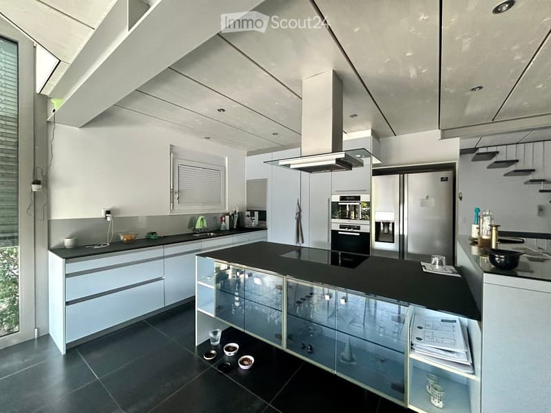 Modern kitchen with white cabinets, black countertops, stainless steel appliances, and a central island with glass-fronted cabinets.