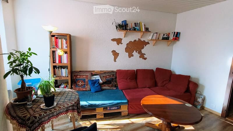 Living room with a red sofa, wooden coffee table, bookshelf, potted plants, and a floor lamp. The walls feature a world map design.