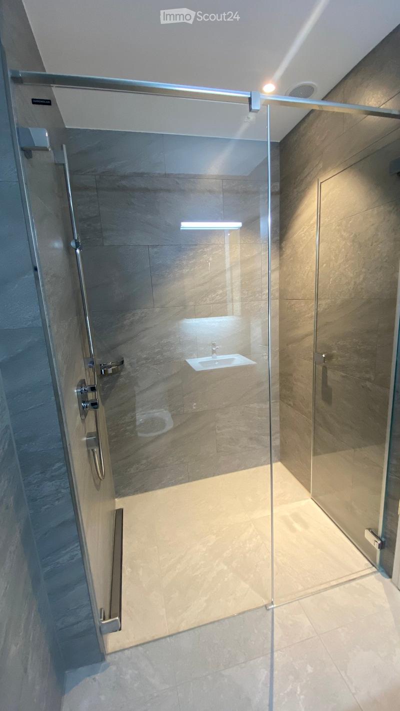 Modern bathroom with a glass-enclosed shower stall, marble tiles, and a built-in sink.