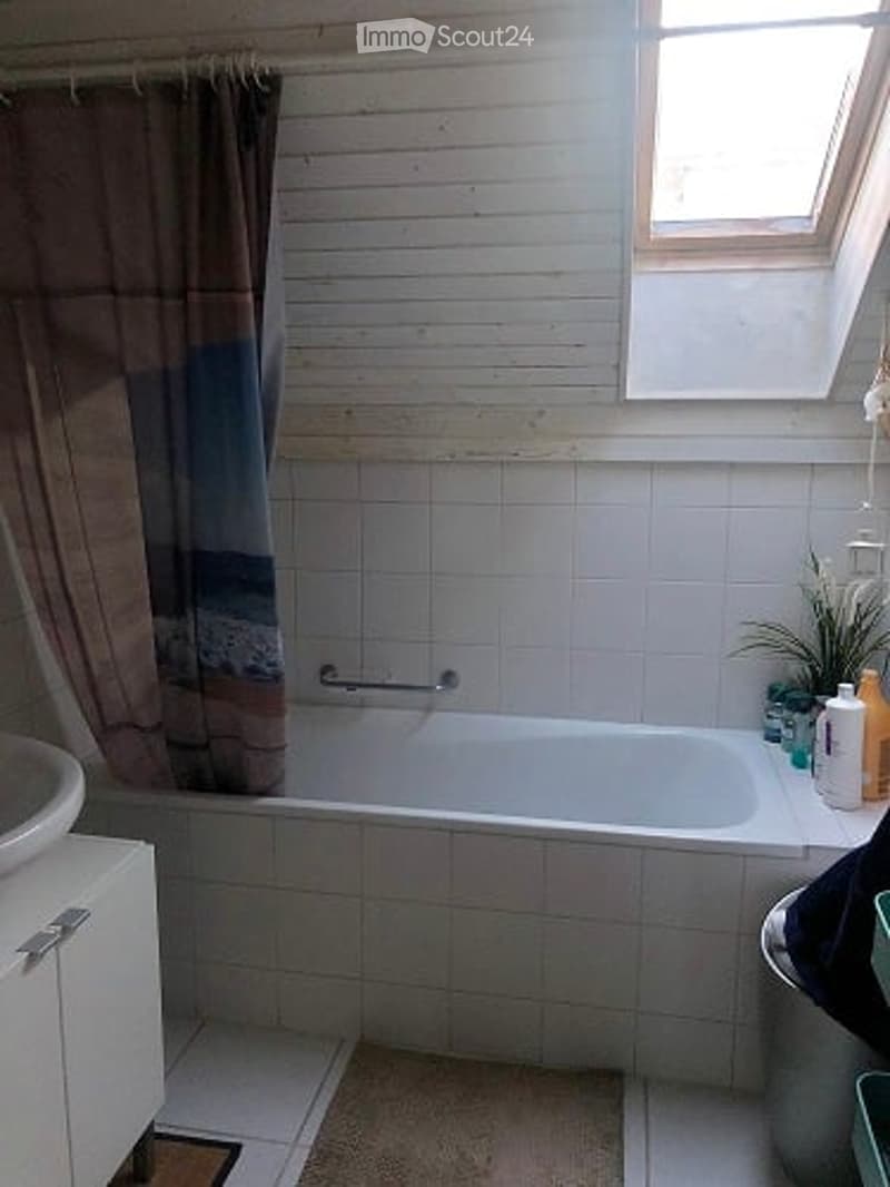 Bathroom with a bathtub, shower curtain, sink, cabinet, and small plant on the edge of the tub.