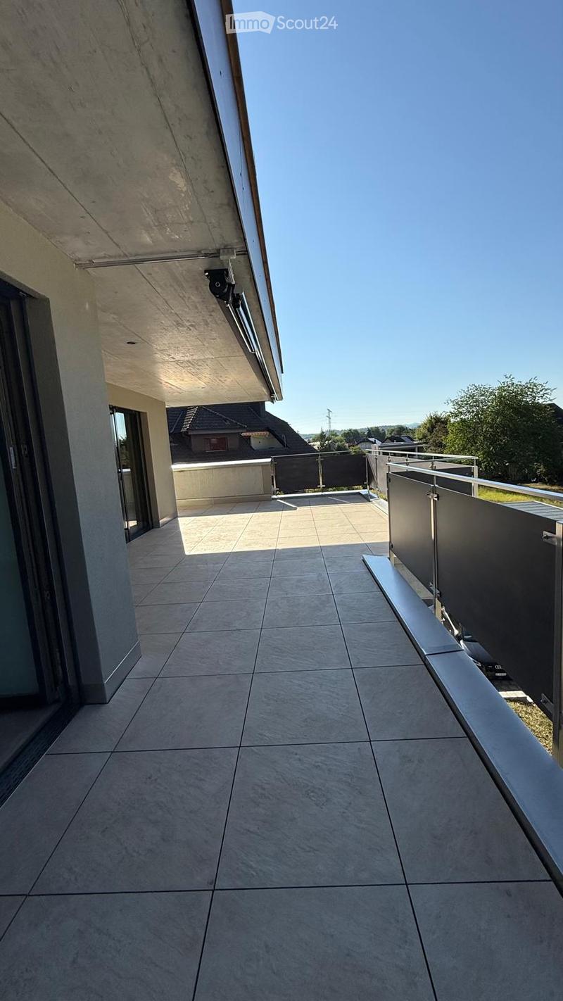 Modern balcony with tiled floor, metal railing, and clear view of the surrounding area.
