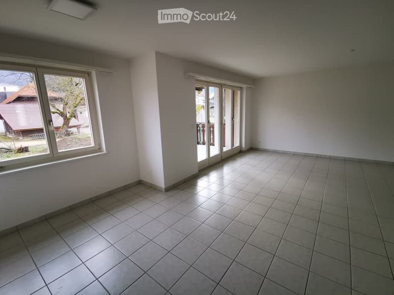 Empty room with tiled floor, large windows, and sliding glass doors leading to a balcony.