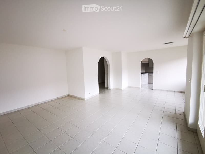 Empty room with white walls and tiled floor, featuring two arched doorways leading to other spaces.
