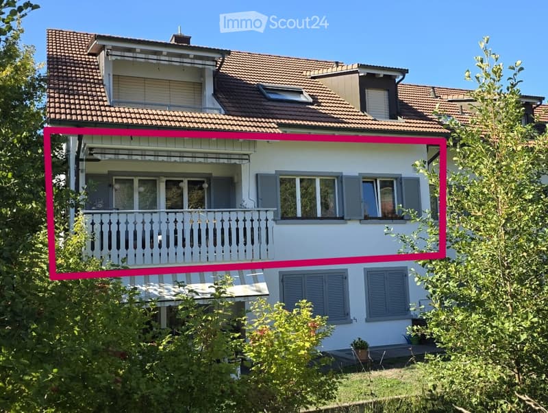 Two-story house with white exterior, grey shutters, and a balcony on the upper floor.