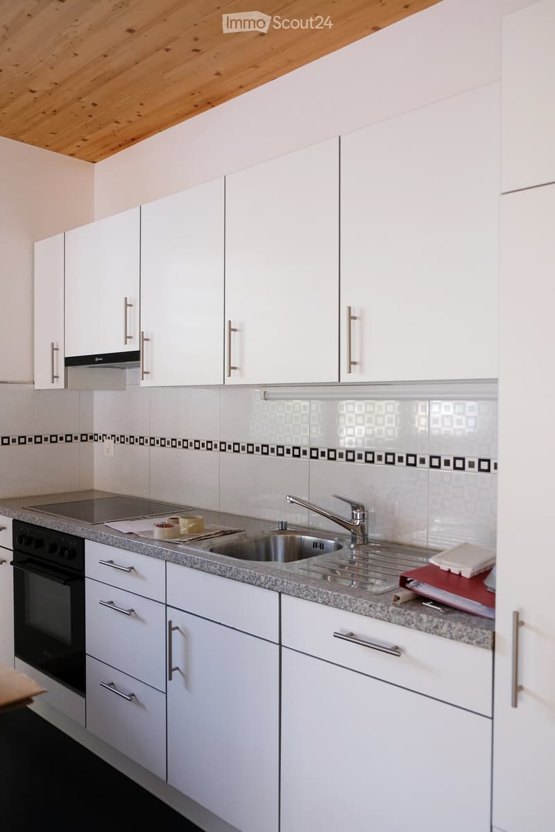 Modern kitchen with white cabinets, granite countertop, stainless steel sink, and built-in oven.