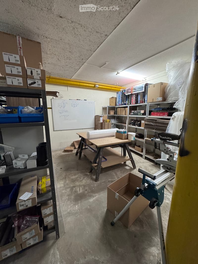 Workshop or storage area with shelves, workbench, tools, and boxes.