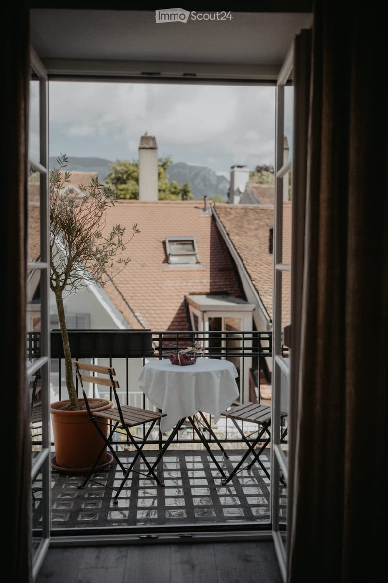 Balcony with tables and chairs, view to mountains and buildings