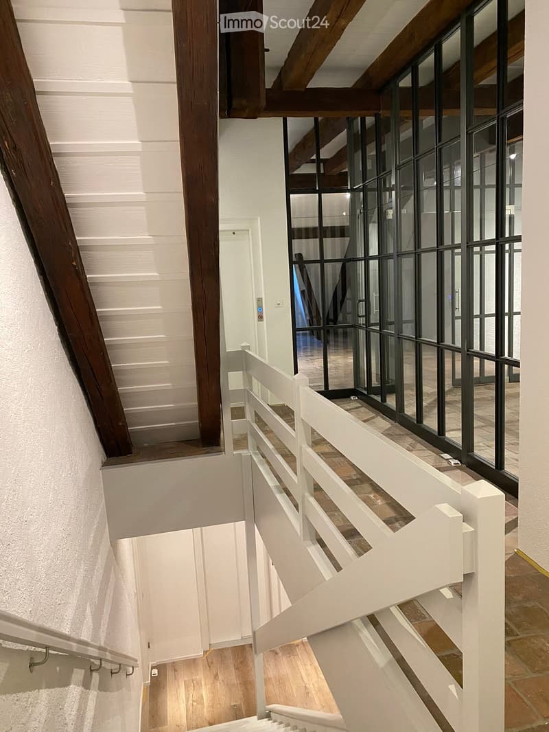Exposed wooden beams, white handrail, wooden staircase, glass wall, white railing, white wall, blue light
