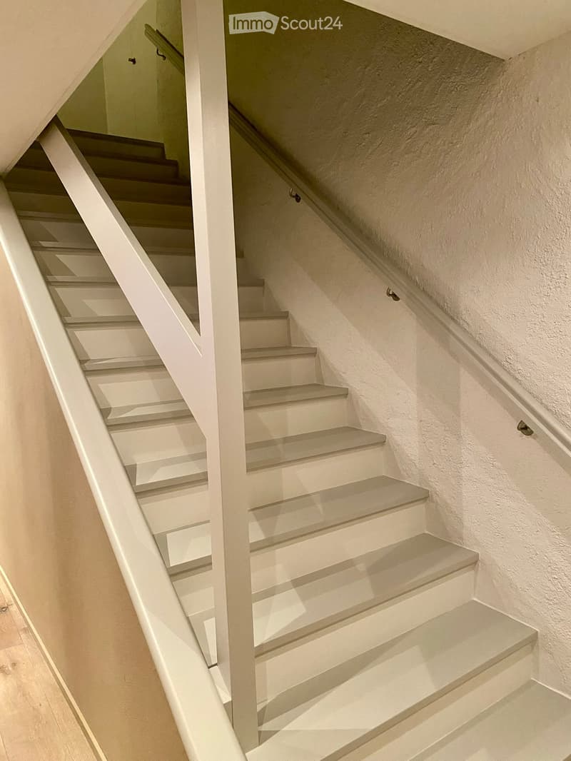 White wooden staircase with handrails leading to the upper floor.