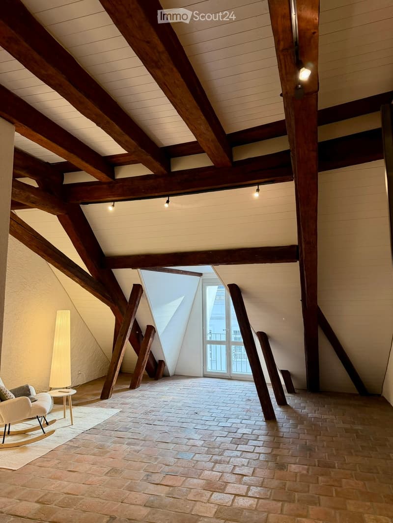 brick flooring, wooden beams, rocking chair, small table, exposed wooden structure