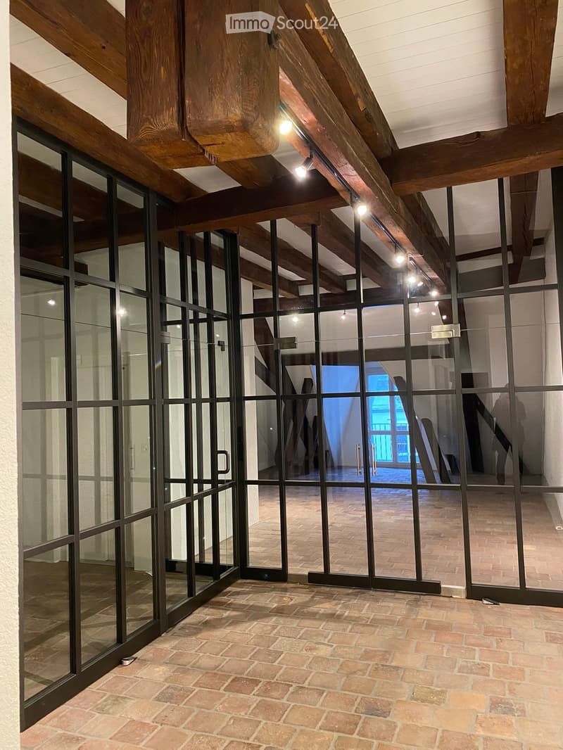 interior room with sliding glass doors, brick flooring, wooden ceiling beams, track lighting