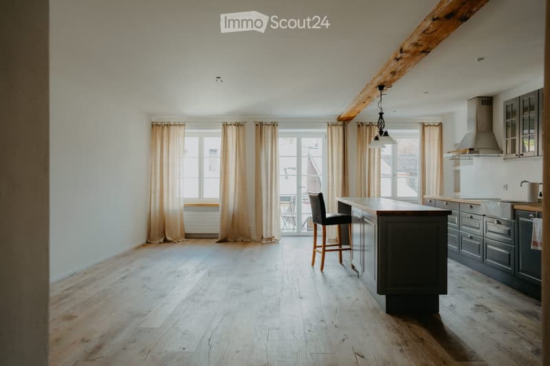 Open kitchen with wooden flooring, large windows, bar stools, stainless steel appliances