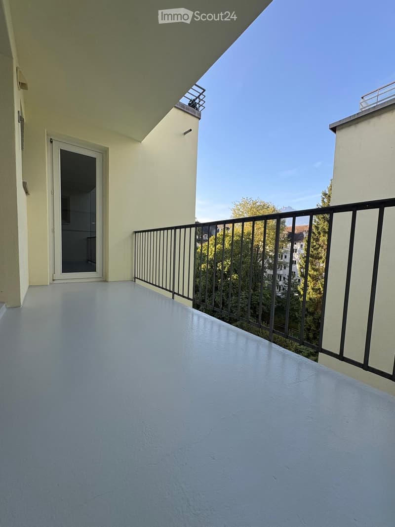 Balcony with white flooring, black metal railing, and a door leading to an interior space.