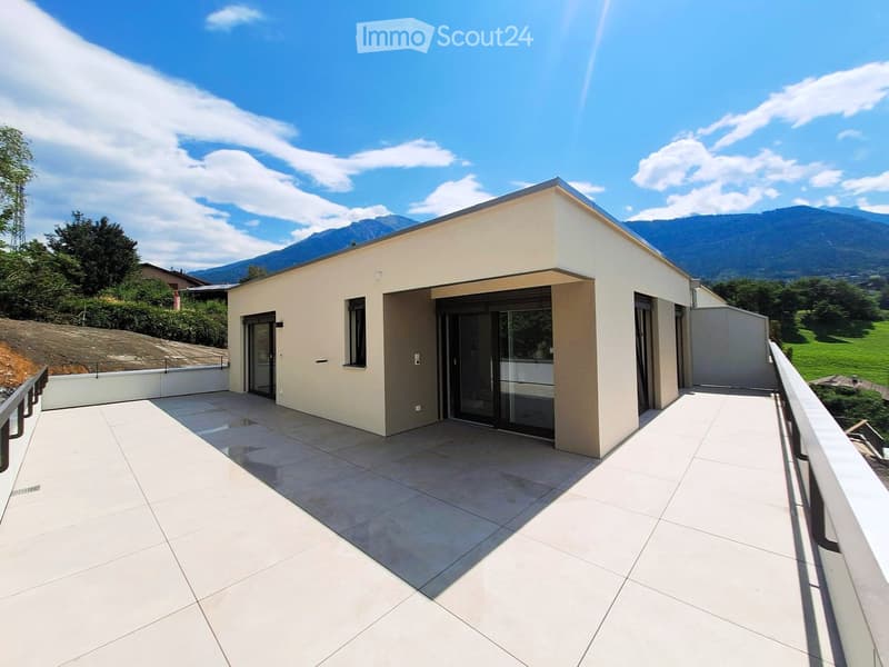 Modern single-story house with a tiled roof, large glass sliding doors, and a spacious balcony overlooking a scenic mountain view.
