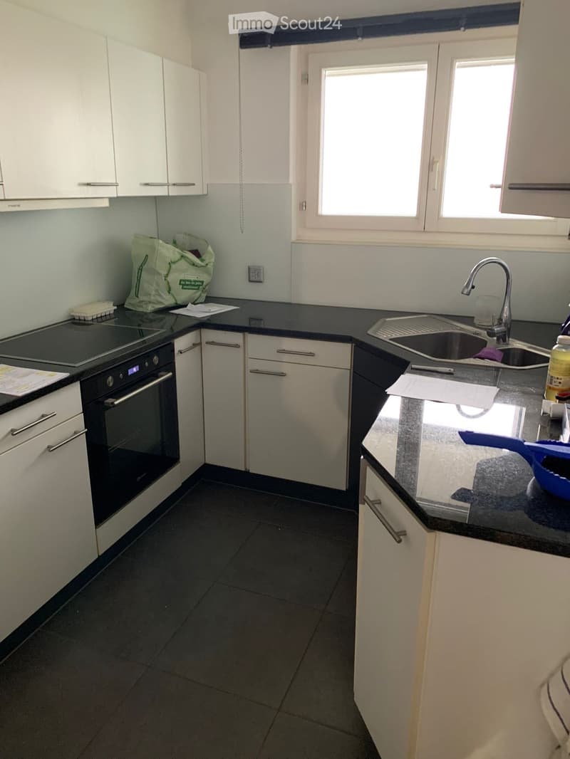 Modern kitchen with white cabinets, black countertops, and stainless steel appliances including an oven and sink.