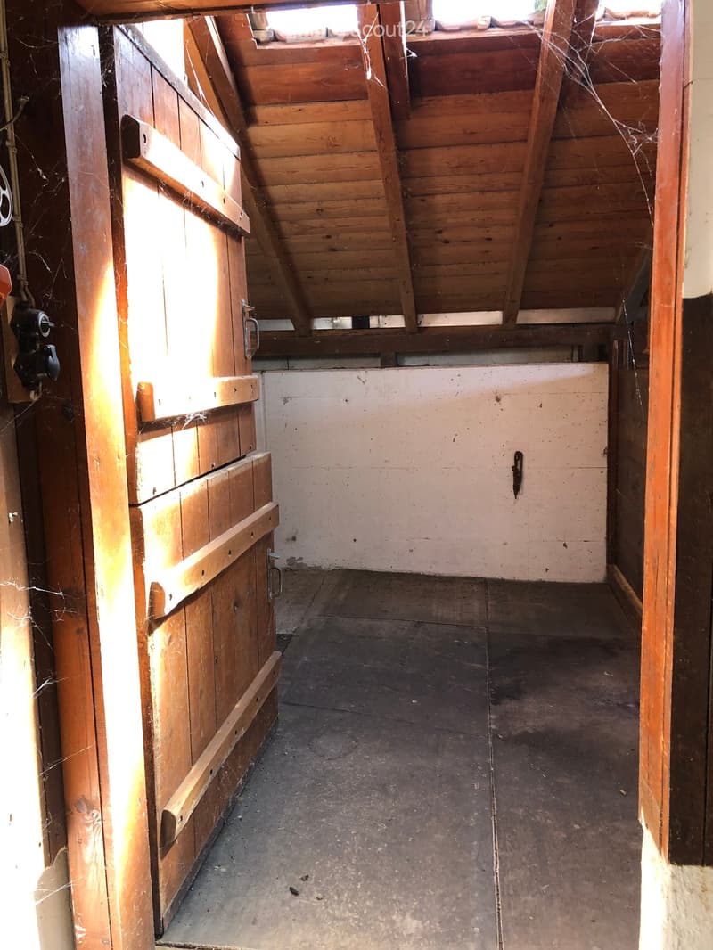 Empty attic space with wooden beams, exposed wooden walls, and a concrete floor. No furniture or equipment present.