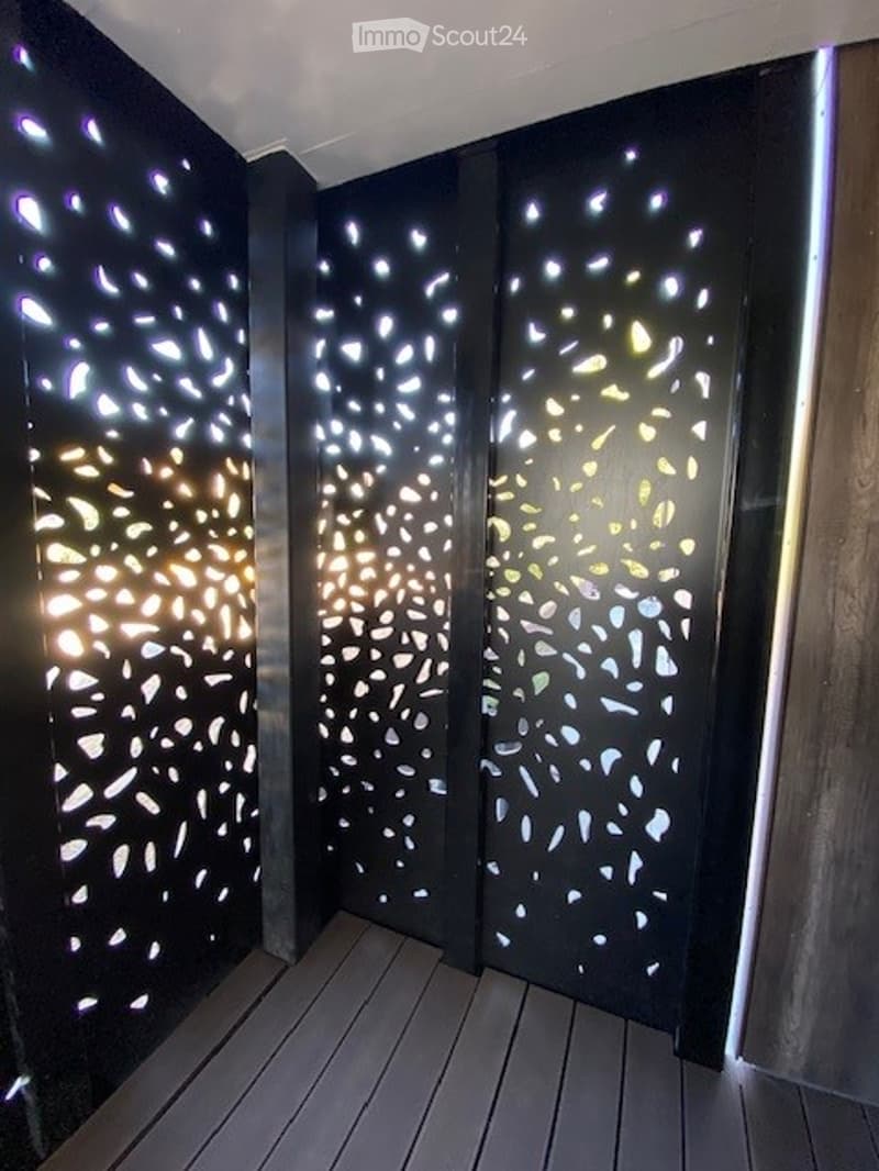 Balcony with dark wooden floor and decorative black screens featuring illuminated patterns.