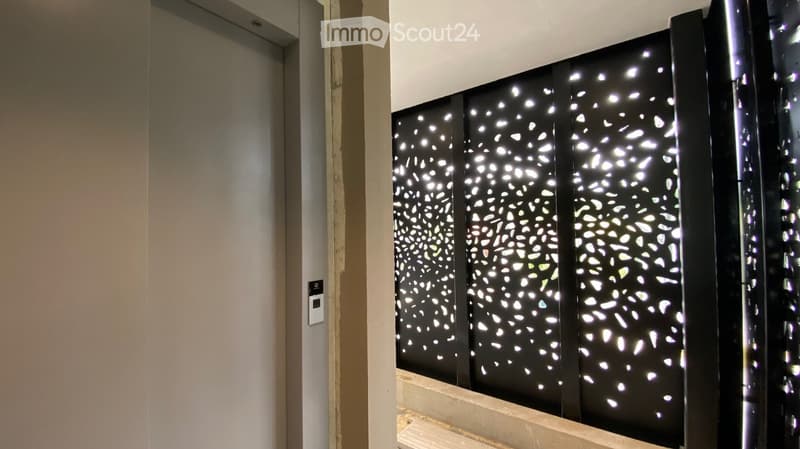 Hallway with modern black decorative panels featuring a white abstract pattern, illuminated by ambient lighting.