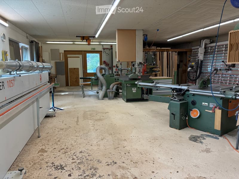 Woodworking workshop with various tools and equipment, including a table saw, woodworking machine, workbench, dust collector, and cabinet.