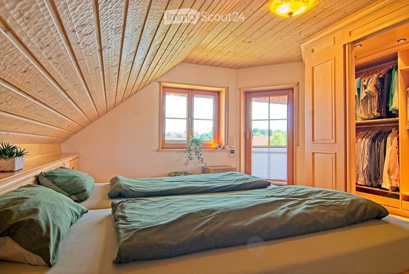 Cozy attic bedroom with wooden beams, two single beds, green bedding, built-in wardrobe, and small plant on nightstand.