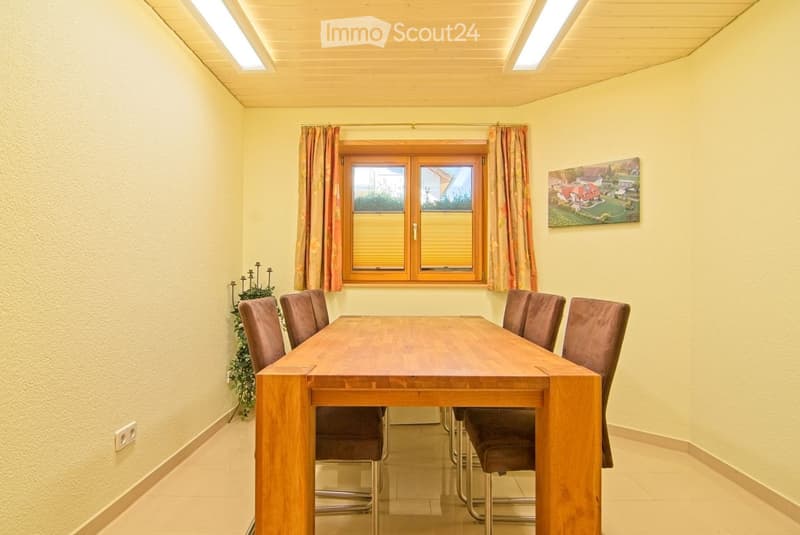 Dining room with a wooden dining table and six chairs, a window with curtains, a candle holder, and a painting on the wall.