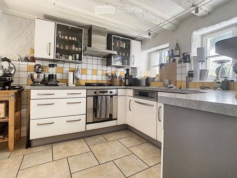 Modern kitchen with white cabinets, stainless steel appliances, tiled backsplash, and a central island with a sink and countertop.
