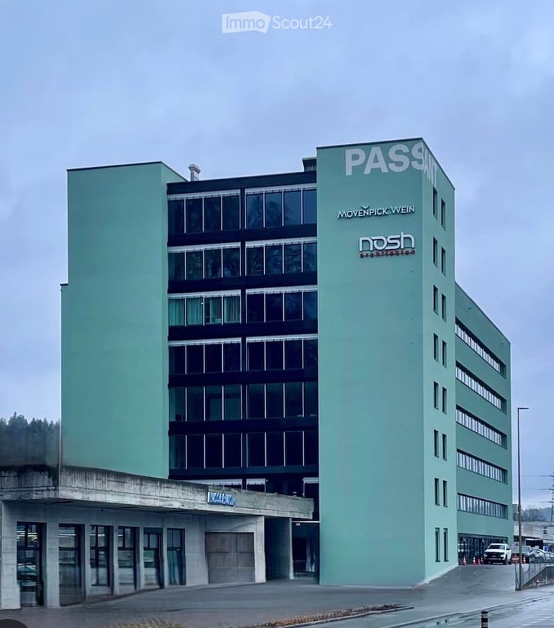 Modern multi-story building with light green facade, large windows, and signage for 'PASS' and 'MOVEMPICK.WEIN'.