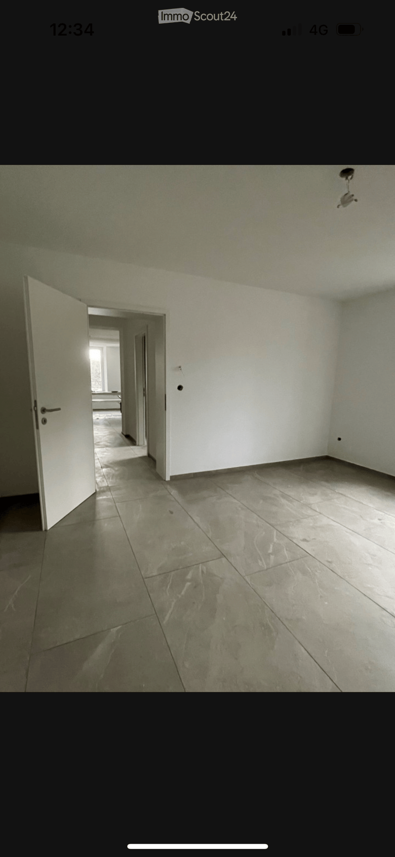 Empty room with tiled floor and white walls, featuring an open doorway leading to another room.