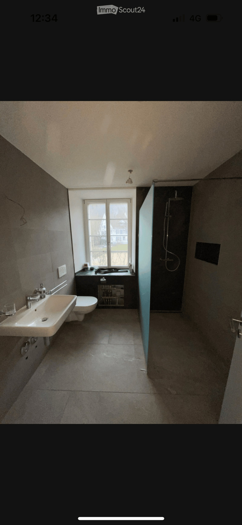 Modern bathroom with a large window, sink, toilet, and separate shower area with glass enclosure.