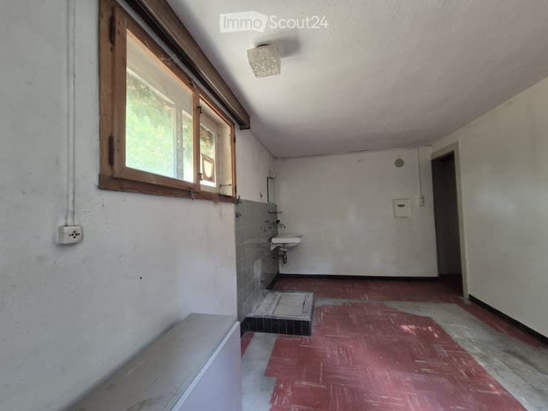 Empty bathroom with a sink, tiled walls, and a window. The floor is covered with a red protective sheet.