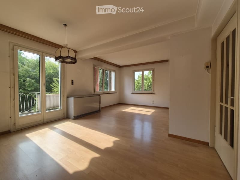 Empty room with wooden flooring, large windows, and a balcony door leading to an outdoor area.
