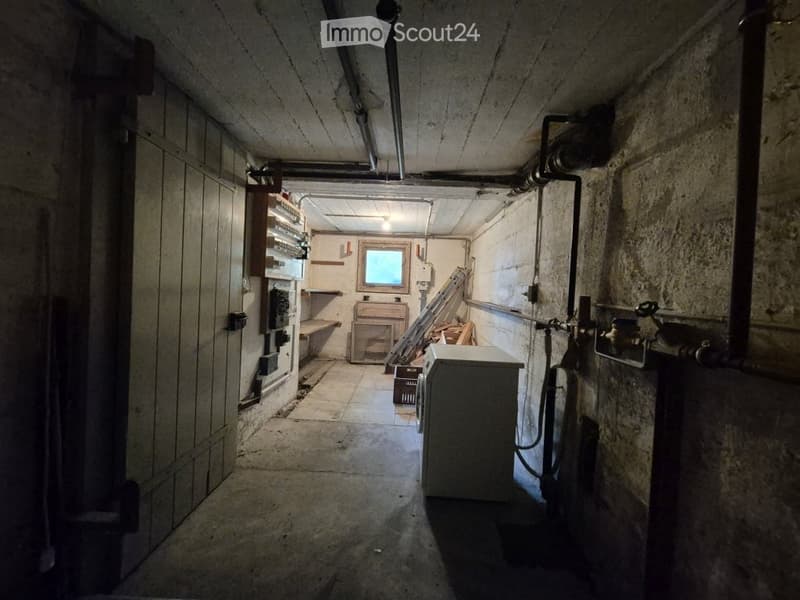Empty basement or utility room with concrete walls, exposed pipes, a small window, and basic shelving units.