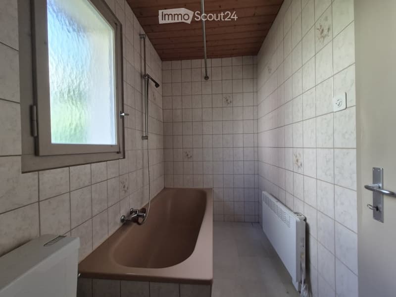 Bathroom with a bathtub, tiled walls, a window, a radiator, and a showerhead.
