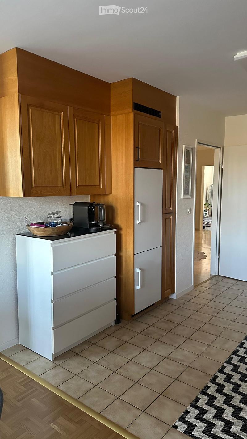 Modern kitchen with light wooden cabinets, white refrigerator, coffee maker on counter, and a bowl on the counter.
