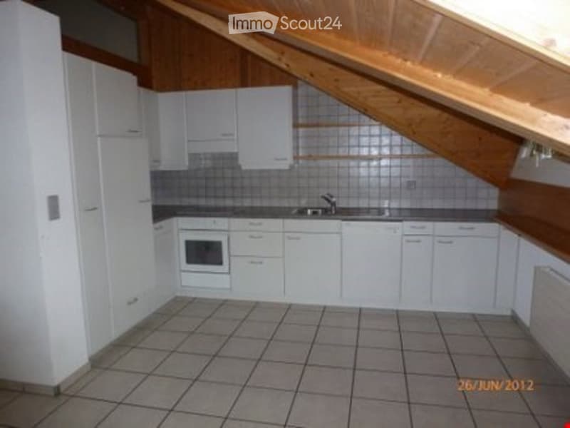 Bright, modern kitchen with white cabinets, a sink, and an oven, featuring a tiled floor and wooden ceiling beams.